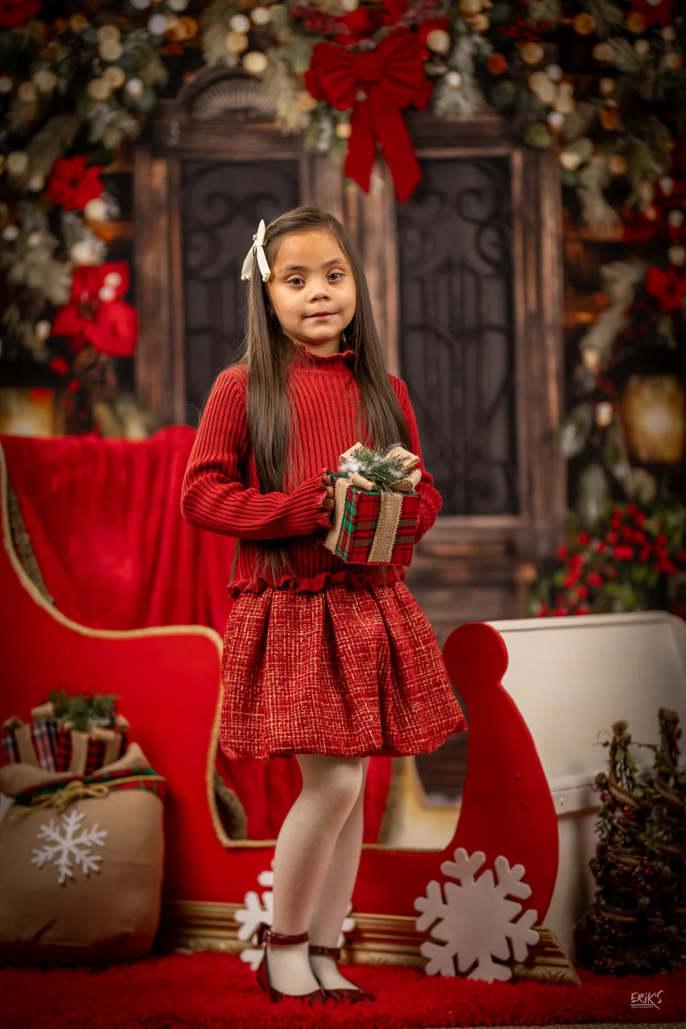 Niña con vestido rojo en el trineo navideño
