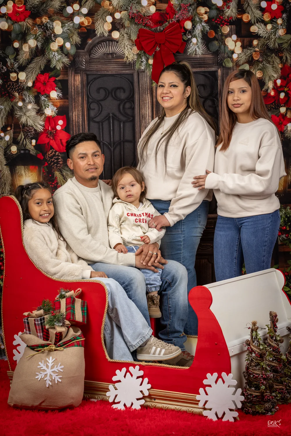 Familia reunida en un trineo rojo junto al árbol