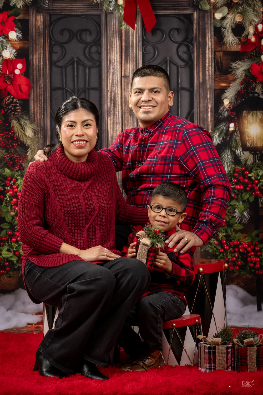 Familia posando con ropa roja y cuadros navideños