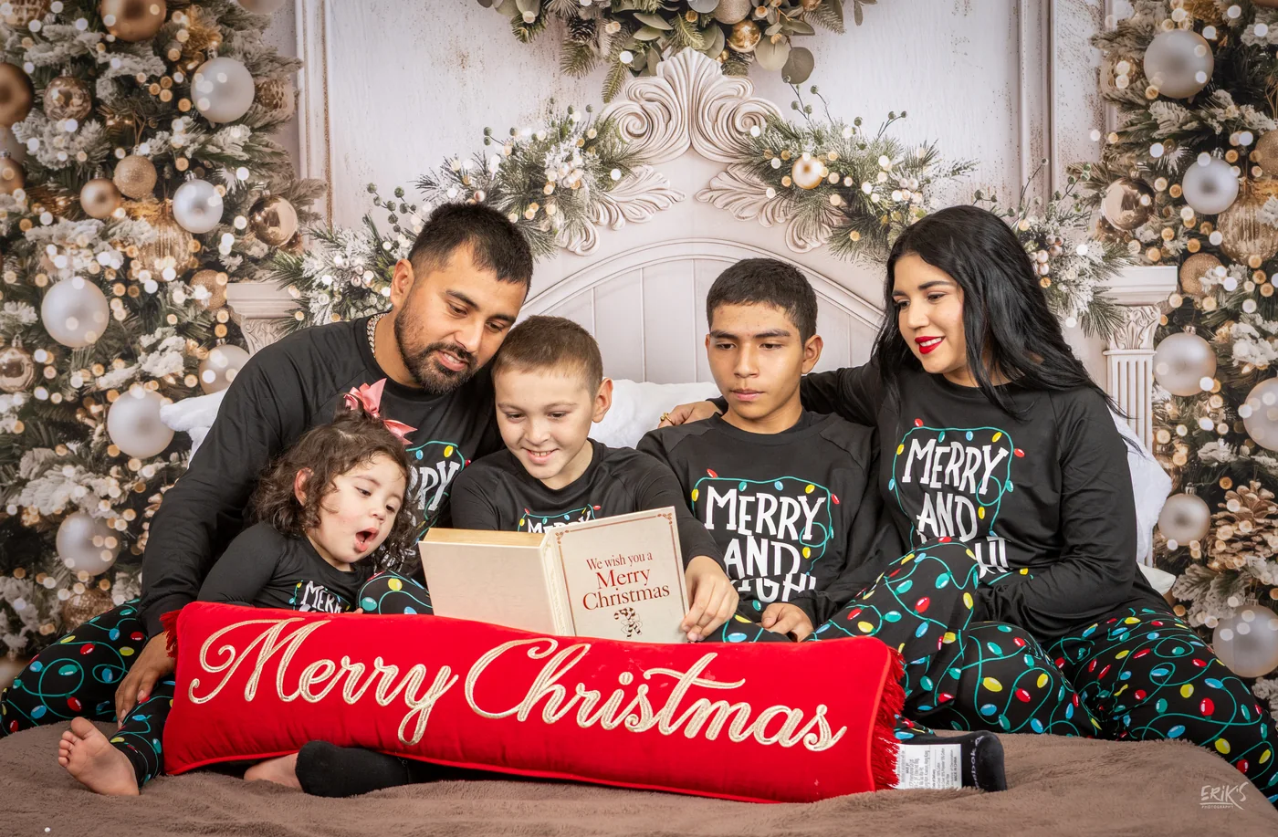 Familia posando con un letrero Merry Christmas