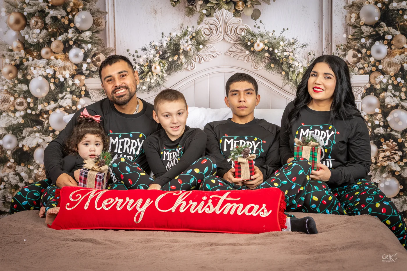 Familia con niños frente a un letrero Merry Christmas